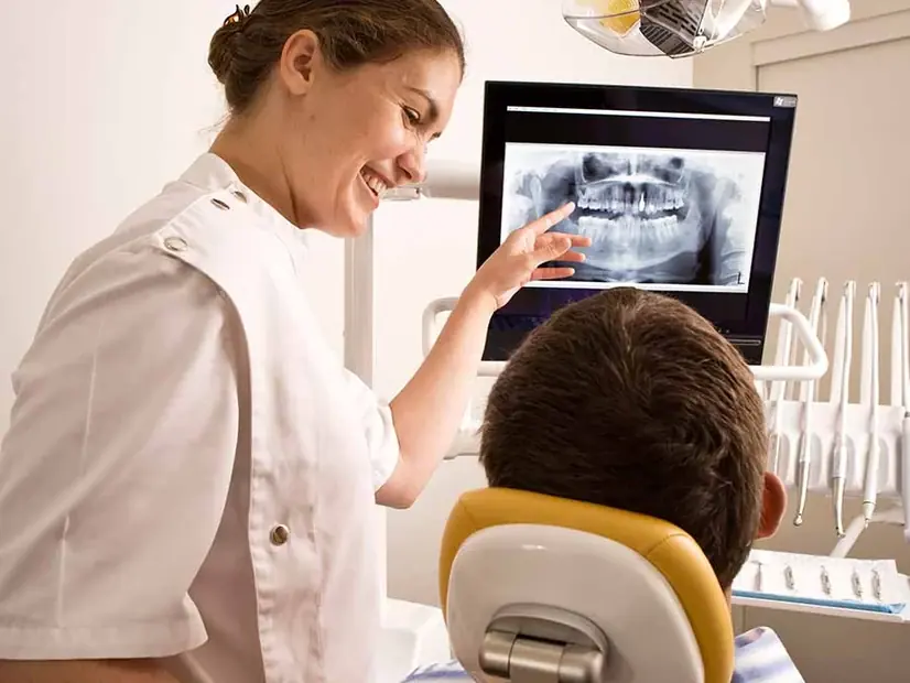 A clinician showing a patient their X-ray on the operatory screen.